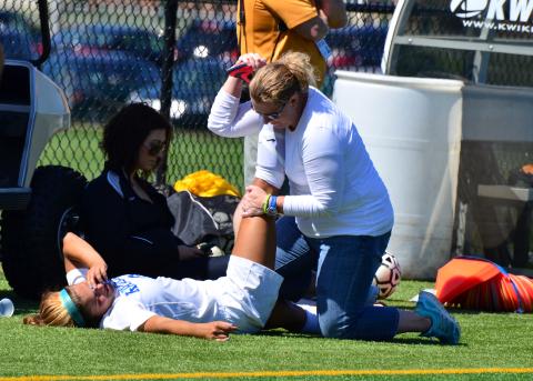 Athletic trainer helping an injured athlete on the sideline