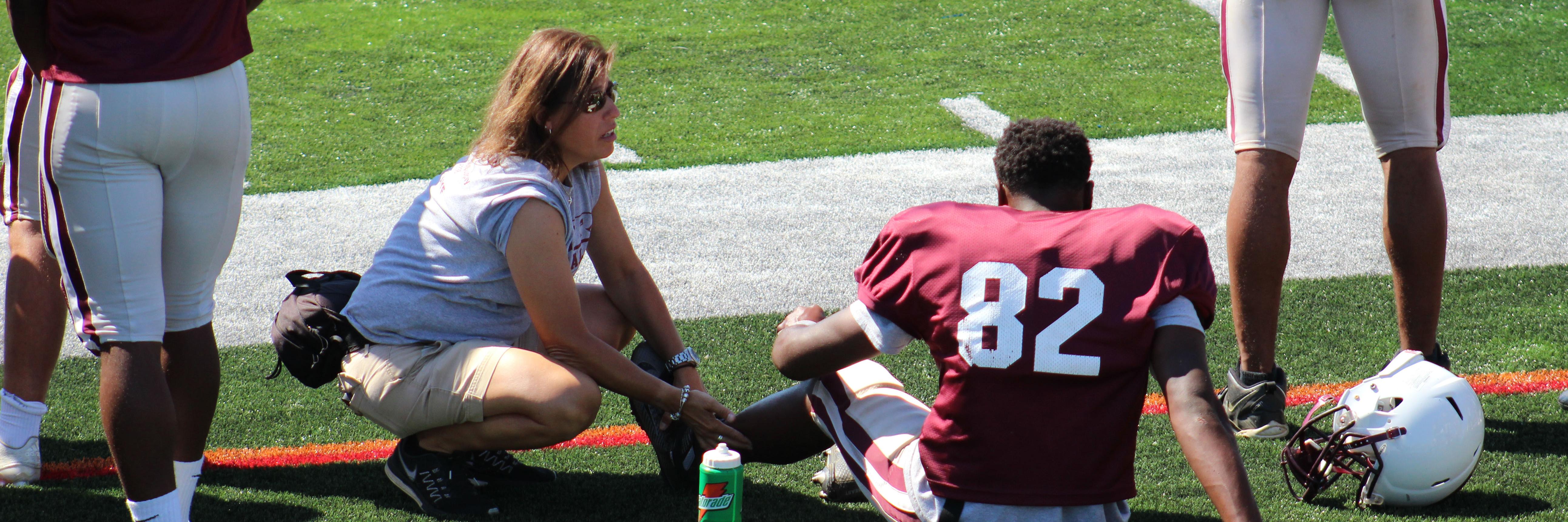 Athletic trainer treating a player on the side of a playing field